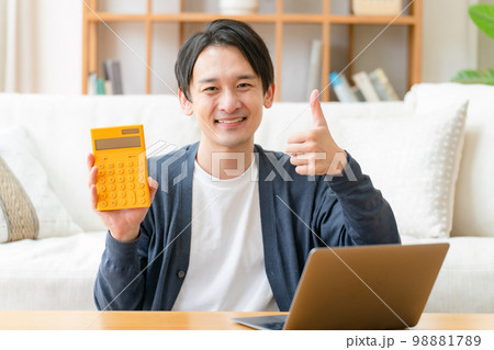 計算機を持って喜ぶミドル男性　サムズアップ 98881789