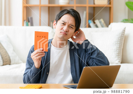 年金手帳を持って悩む男性 98881790