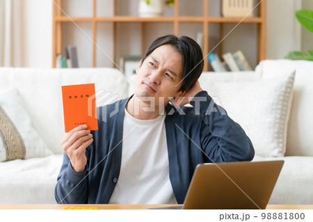 年金手帳を持って悩む男性 98881800