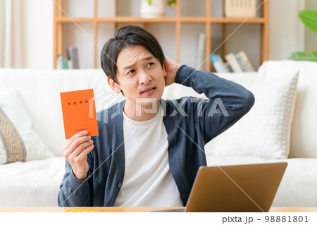 年金手帳を持って悩む男性 98881801