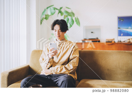 ソファに座ってスマホを見る男性 98882080