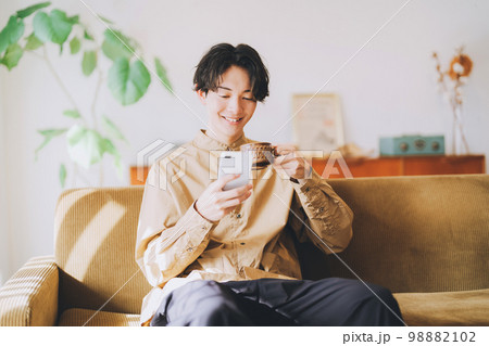 コーヒーを飲みながらスマホを見る男性 コーヒーを飲みながらスマホを見る男性 98882102