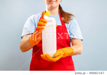 Woman in glove holding a plastic detergent bottle on blue background 98882167