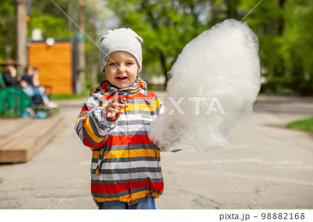 Child boy in an amusement park eats cotton candy Child boy in an amusement park eats cotton candy 98882168