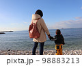 砂浜で海を眺める親子 98883213