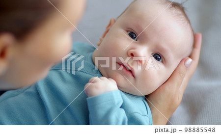 Newborn baby happy to looking on his mom . Happy mother spends time with her child. Mother playing with an infant kid.   Infant with blue eyes happy being with mama. Maternity and childcare concept. 98885548