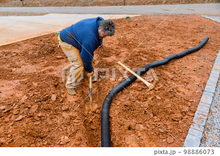 During major rainfall worker digs trench so as to lay drainage pipe for collect rainwater 98886073