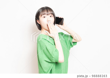 スマホを使いながら驚いている若い女性 98888163