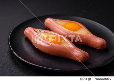 Composite concept of fried eggs inside a cut sausage with spices 98888665
