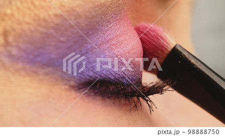 Make-up artist applies makeup to the upper eyelid, close-up.  Makeup artist applies a bright eye shadow with a makeup brush. Tutorial master class of professional makeup. 98888750