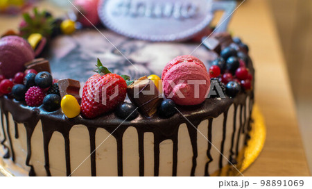 A cake for a children's birthday with berries, fruits, macaroons, depicting a cute Persian kitten 98891069