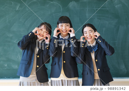 教室の黒板の前で友達とポーズをとる女子高生 98891342