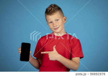 Online Offer. Smiling preteen boy pointing at blank smartphone in hand 98892976