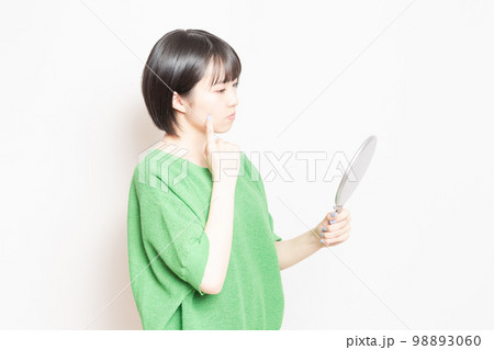 手鏡で顔を見ている若い女性 手鏡で顔を見ている若い女性 98893060