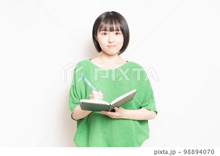 ノートにボールペンで文字を書く若い女性 98894070