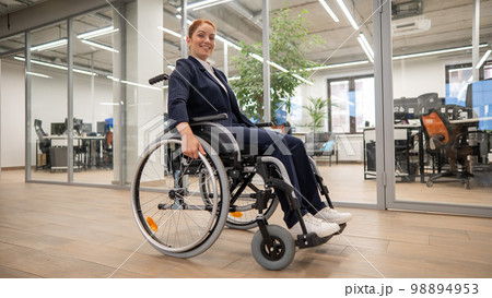 Caucasian woman wheelchair in open space office. 98894953