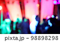 Blurred silhouettes of crowd of people dancing on the dance floor of a night club under the light of colored spotlights and lasers. 98898298
