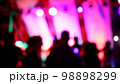 Blurred silhouettes of crowd of people dancing on the dance floor of a night club under the light of colored spotlights and lasers. 98898299