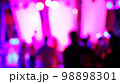 Blurred silhouettes of crowd of people dancing on the dance floor of a night club under the light of colored spotlights and lasers. 98898301