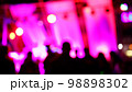 Blurred silhouettes of crowd of people dancing on the dance floor of a night club under the light of colored spotlights and lasers. 98898302