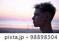 Thoughtful guy looks into the distance on the beach during sunset 98898304