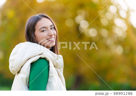 Sensual young woman turning to smile at the camera outdoors 98901286