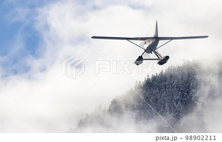 Floatplane flying over the Canadian Mountain Landscape. Adventure Composite 98902211