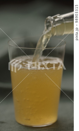 pour yellow drink in tumbler glas on linen cloth 98903315