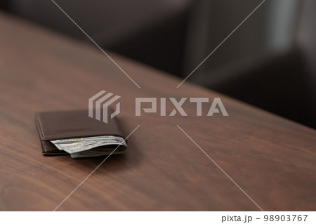 Full grain leather wallet with us dollars on walnut table 98903767