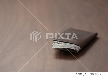 Full grain leather wallet with us dollars on walnut table 98903768