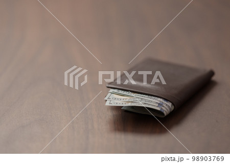 Full grain leather wallet with us dollars on walnut table 98903769