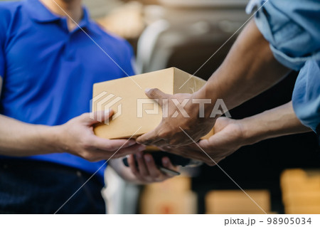 Male hand accepting delivery of box from delivery man in the morning. 98905034