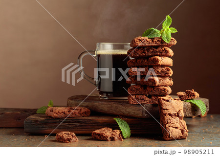 Pieces of fresh brownie with mint and a cup of black coffee. 98905211