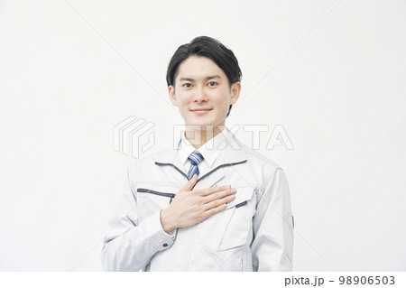 胸に手を置く作業着の男性のポートレート　白背景 98906503