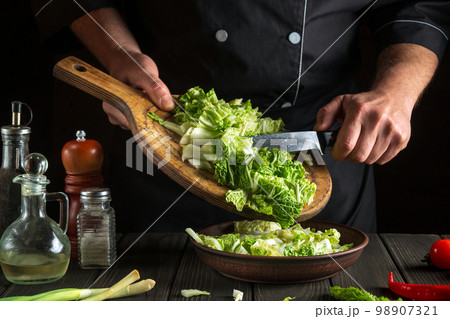 Professional chef makes a fresh napa cabbage salad. Preparation for slicing in the kitchen. Vegetable diet idea Professional chef makes a fresh napa cabbage salad. Preparation for slicing in the kitchen. Vegetable diet idea 98907321