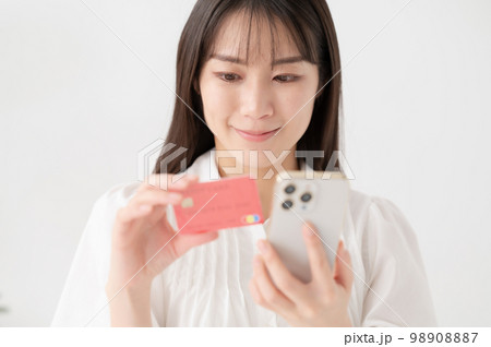 スマートフォンとカードを持つ女性 98908887