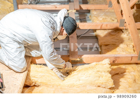 man insulates the roof and ceiling of the house with glass wool 98909260