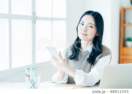 リビングでテレワークをする若い女性。 リビングでテレワークをする若い女性。 98911343