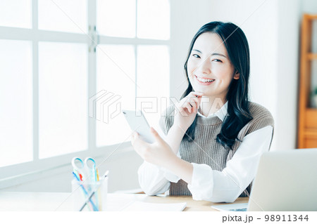 リビングでテレワークをする若い女性。 リビングでテレワークをする若い女性。 98911344