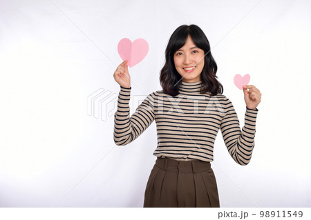 Beautiful young asian woman holding a paper heart while standing against white background. Beautiful young asian woman with paper heart. Beautiful young asian woman holding a paper heart while standing against white background. Beautiful young asian woman with paper heart. 98911549