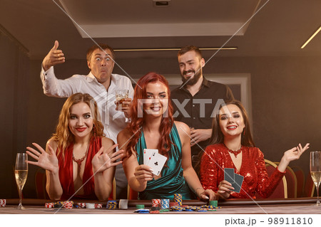 Group of a young wealthy friends are playing poker at a casino. 98911810