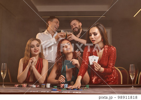 Group of a young wealthy friends are playing poker at a casino. 98911818