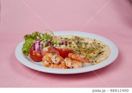 breakfast plate scrambled eggs with shrimps and tomatoes, on monochromatic delicate background, side view breakfast plate scrambled eggs with shrimps and tomatoes, on monochromatic delicate background, side view 98912400