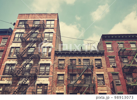 Old brick townhouses with fire escapes, color toning applied, New York City, USA. 98913073