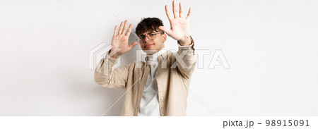 Image of reluctant and annoyed man raising hands up to block offer, refusing and asking to stop, telling no, declining something, standing on white background 98915091