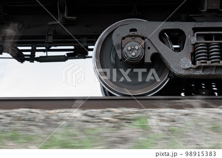 Wheels and bogie of freight train moving fast along railroad. 98915383