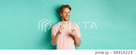 Funny redhead guy congratulating you, pointing fingers at camera and smiling, making choice, standing in t-shirt over mint background 98916229