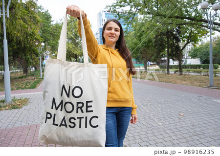 A woman shows a fabric reusable bag with the text no more plastic. 98916235