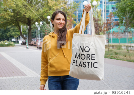 A woman shows a fabric reusable bag with the text no more plastic. 98916242