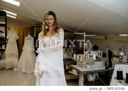 A girl in a boho wedding dress in a sewing workshop. A girl in a boho wedding dress in a sewing workshop. 98916589